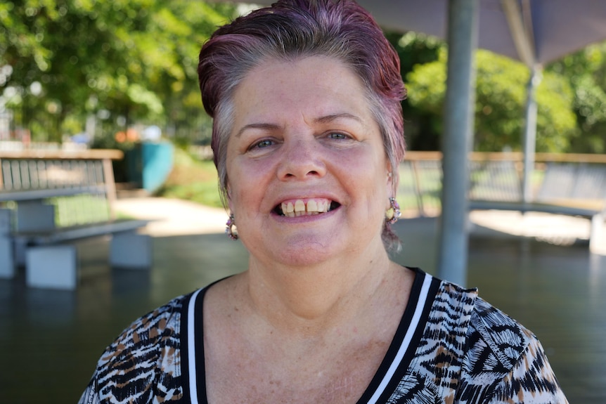 a woman sits on a park bench and smiles at the camera