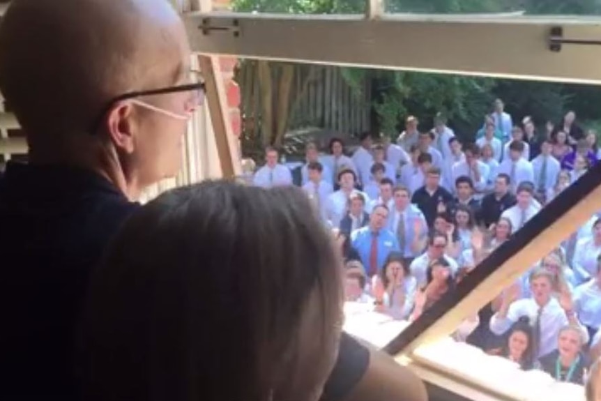 A still from the viral Facebook video of Ellis looking out his window to students singing.