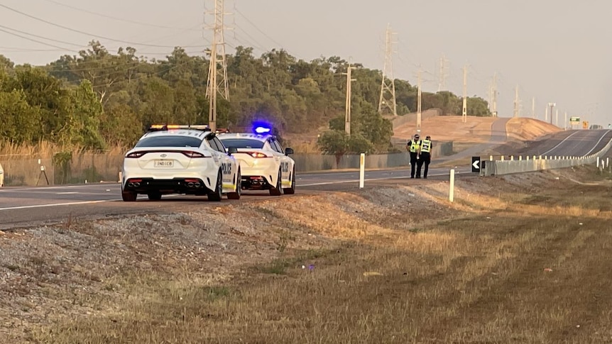 Two police cars with flashing lights parked along a closed off section of highway.