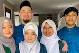A family of five poses for a photo in traditional Islamic dress
