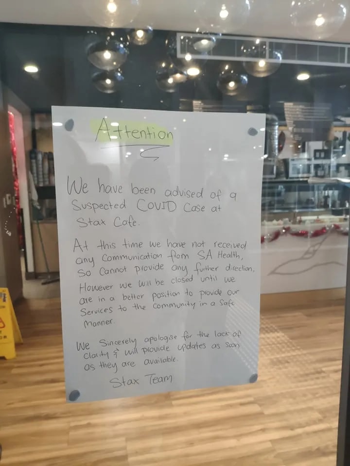 A sign on a shop window stating the business is closed due to a suspected COVID case