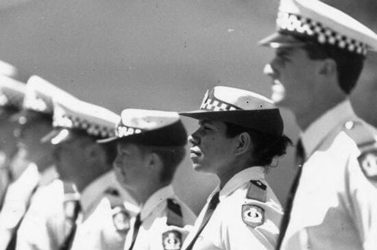 A black and white photo of Leanne Liddle's police graduation shows her standing second in a line of police officers in uniform.