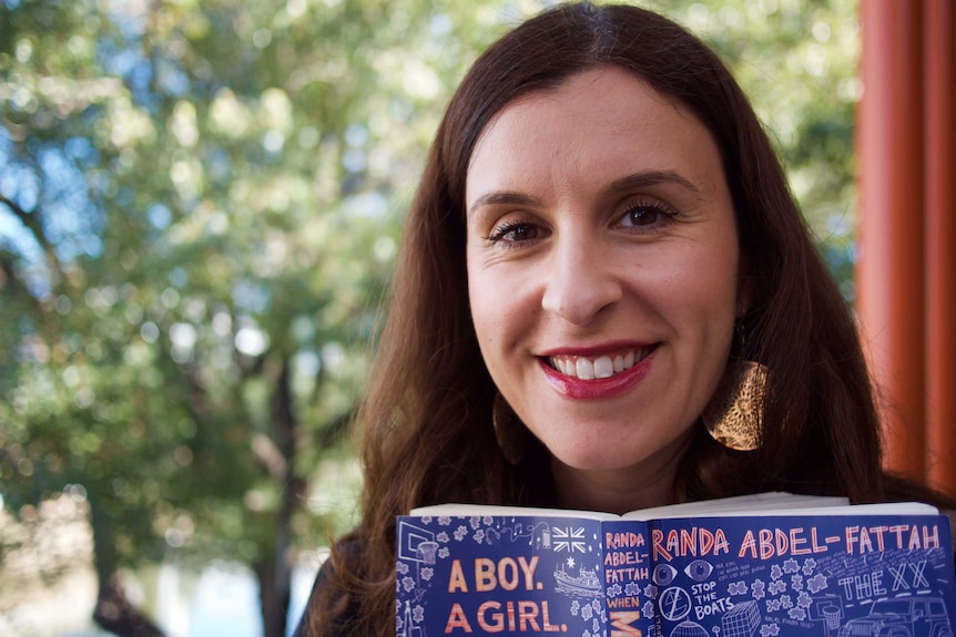 A portrait of Randa Abdel-Fattah holding her latest book, When Michael Met Mina.