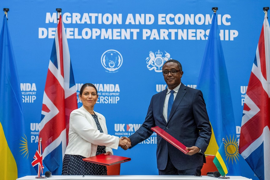 Man and woman shake hands for cameras.