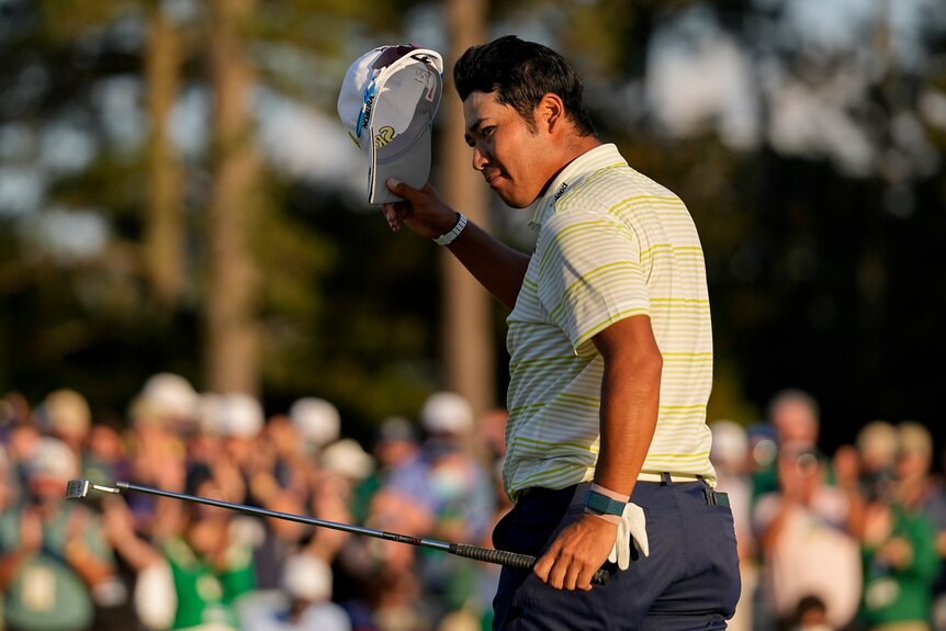 Hideki Matsuyama holds his hat and his putter