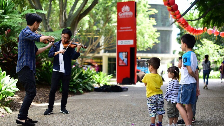 Children watch Eddy Chen and Brett Yang play violin