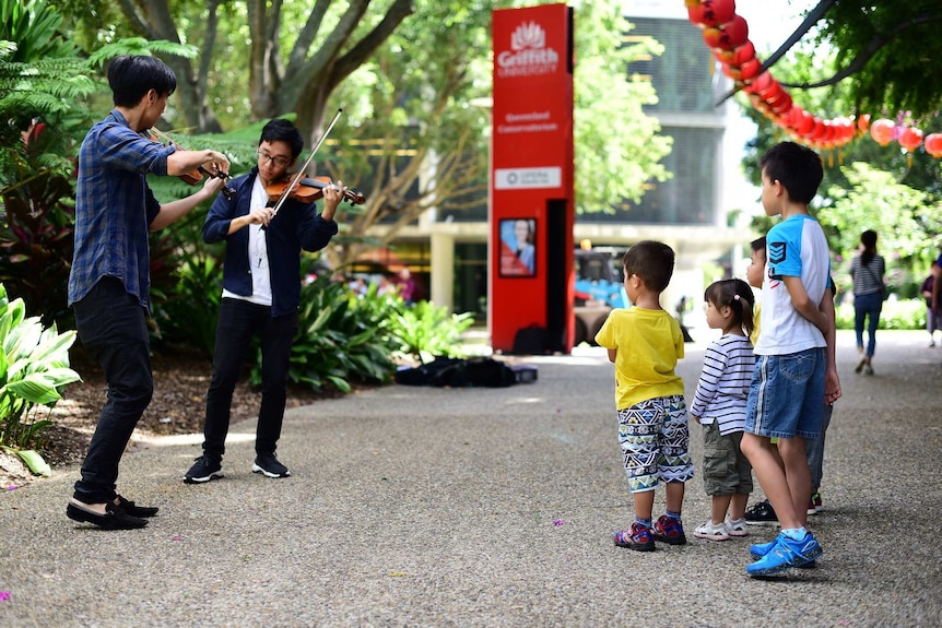 Children watch Eddy Chen and Brett Yang play violin