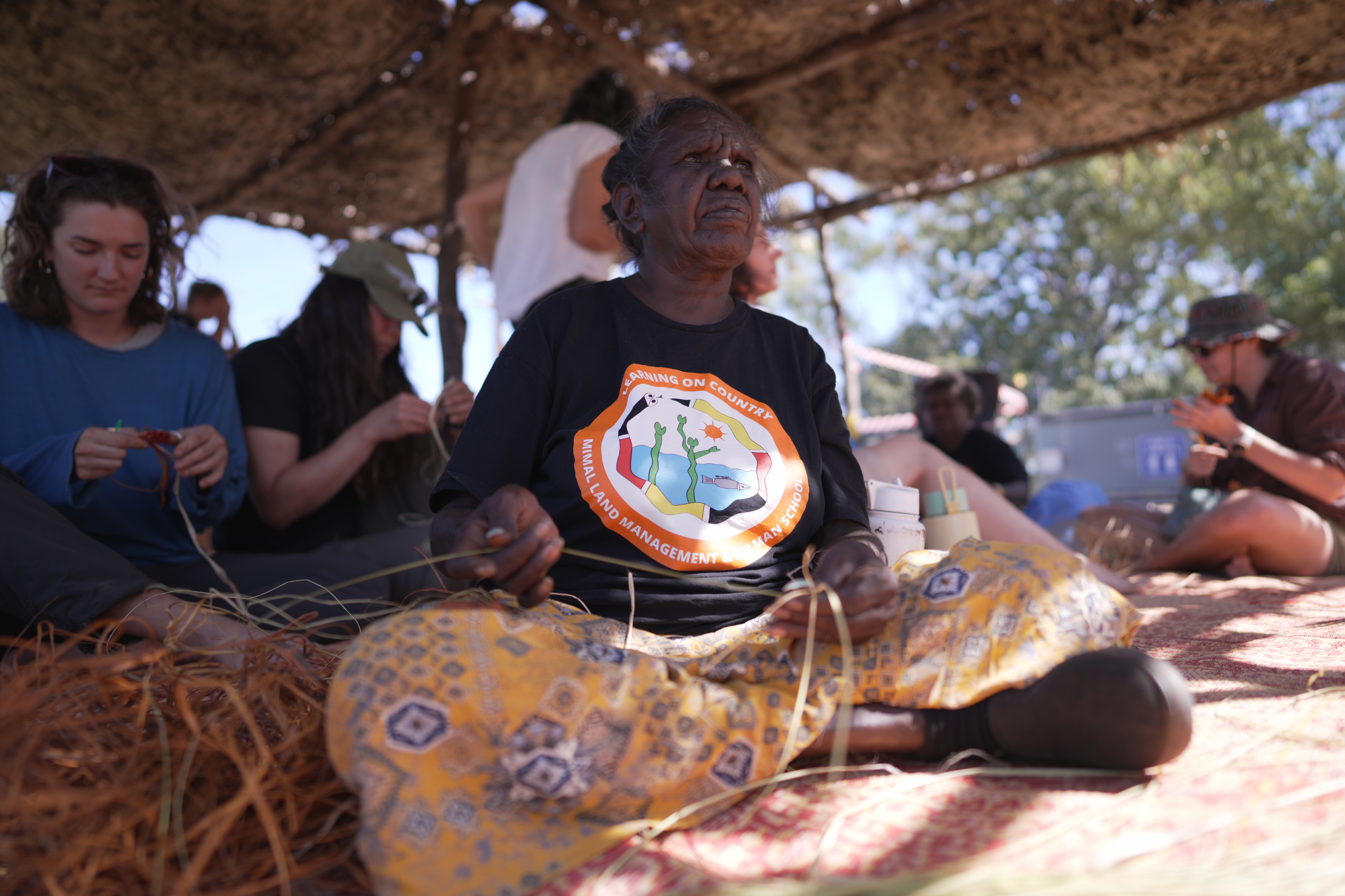 A woman sits weaving.