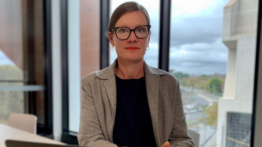 Kate Noble sits at a desk with a laptop in an office building.