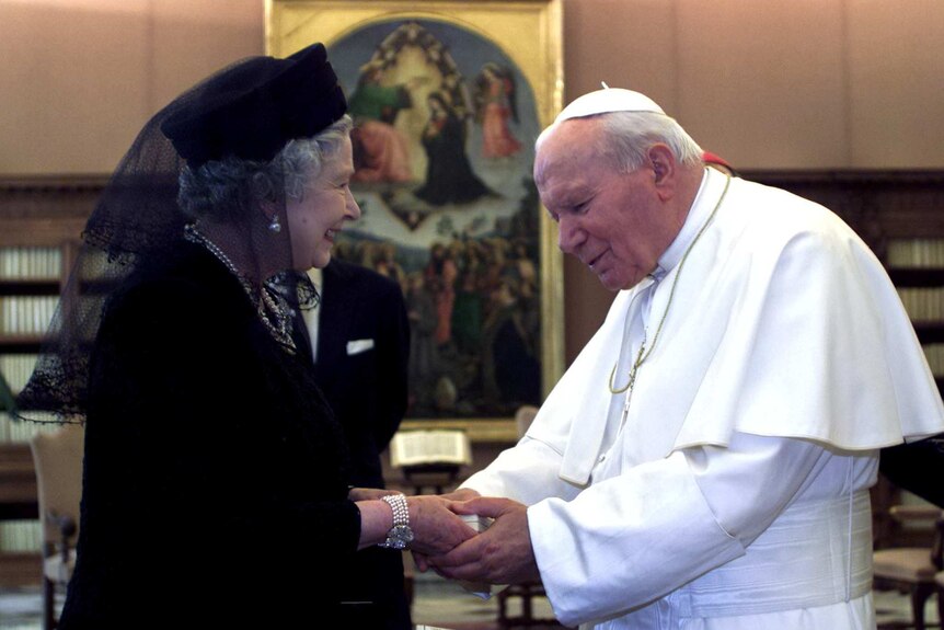 Queen Elizabeth II smiles as she shake hands with Pope John Paul II.