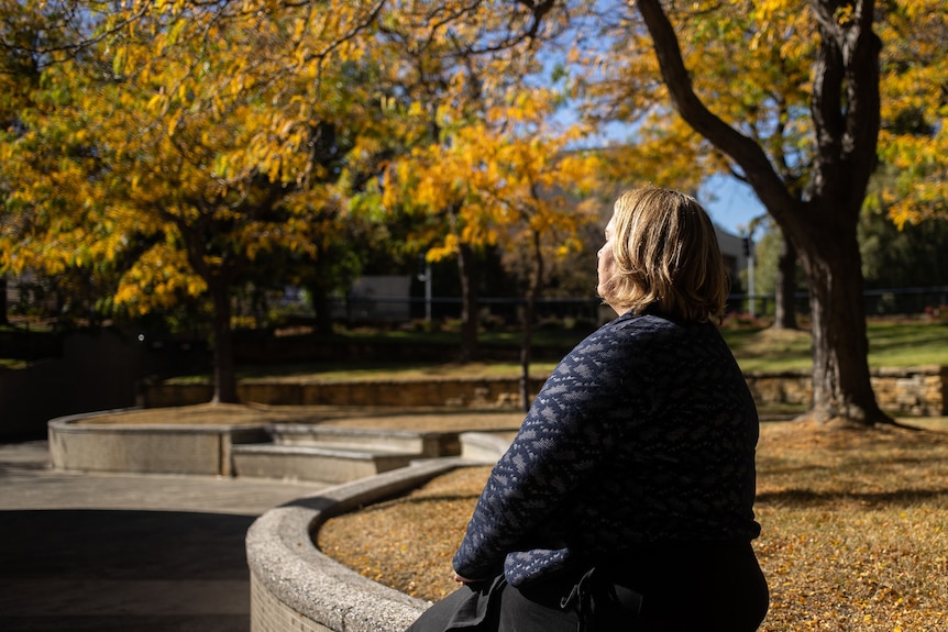 Bron Larkins sits under a tree with her eyes closed.