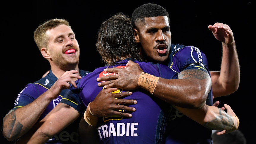 Three Melbourne Storm NRL players embrace after a try was scored against Wests Tigers.