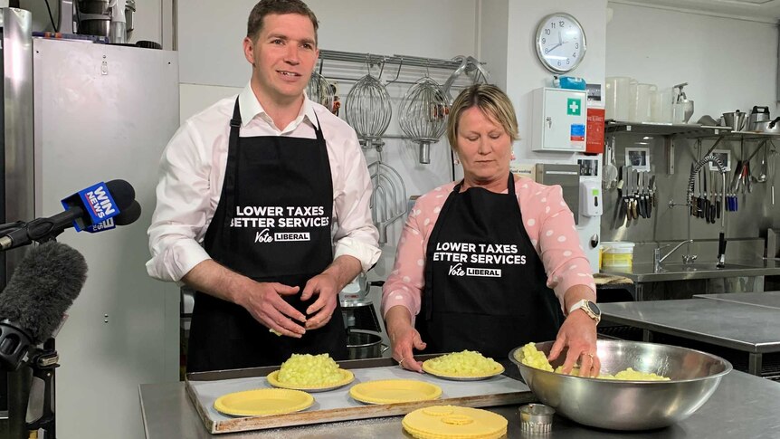 Canberra Liberals leader Alistair Coe making pies with MLA Nicole Lawder in aprons with a party slogan on them.