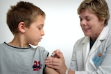 A young boy receives a vaccine shot from a woman in a lab coat