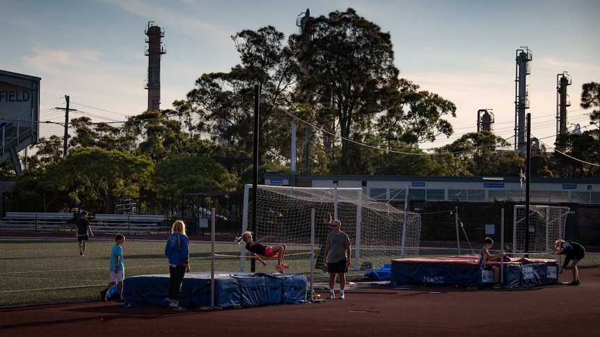 Children perform high jump on an athletics field