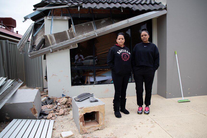 Ms Camp with her daughter Jenae Fynn standing at the front of the damaged home.