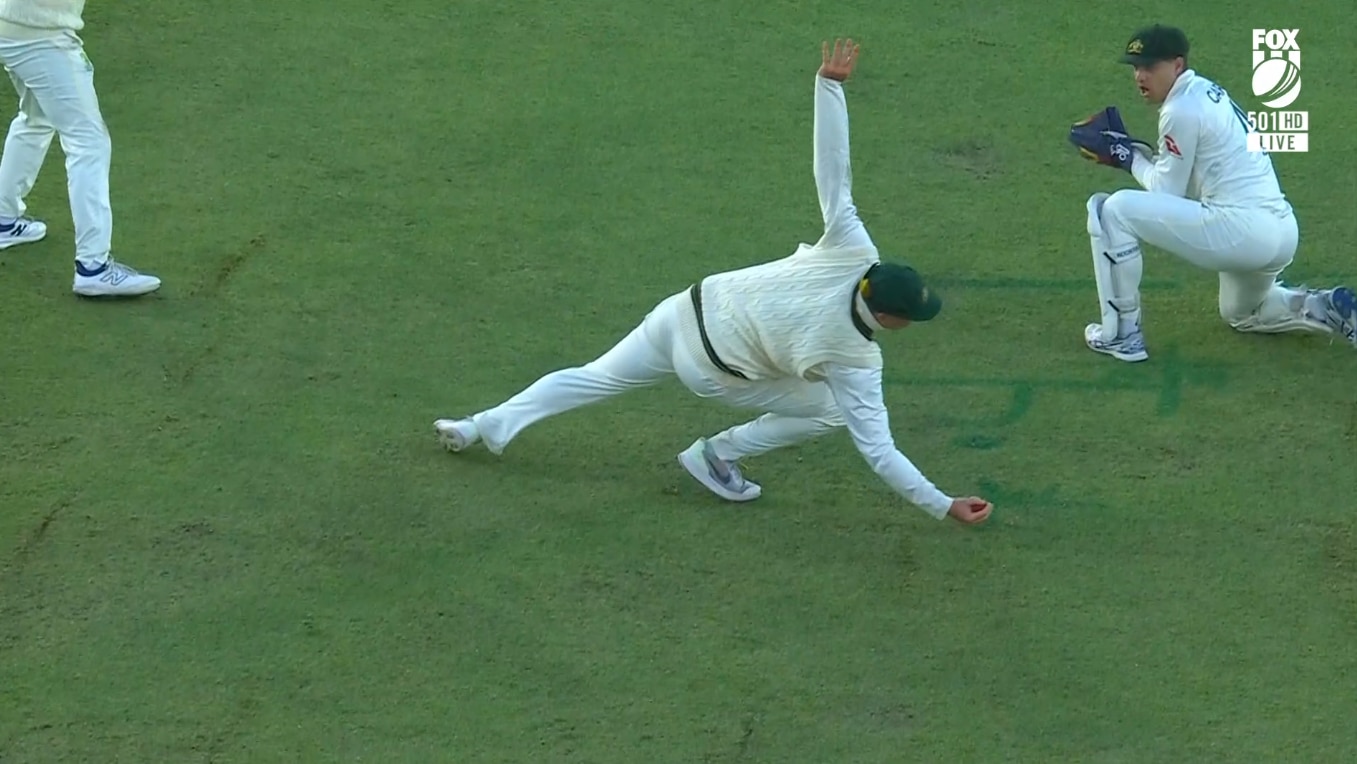 A cricket player dives to his right and takes a catch