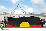 An Aboriginal flag is unfurled outside parliament house in Canberra