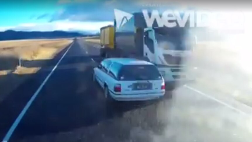 A truck veers onto the side of the road to avoid a car travelling in the wrong lane.