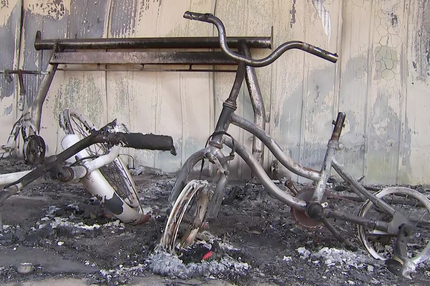 A burned bike sits among bushfire ash