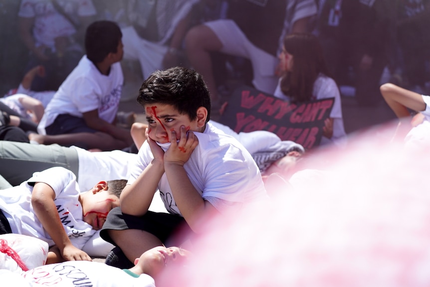 A young boy with fake blood on face at pro-Palestinian rally