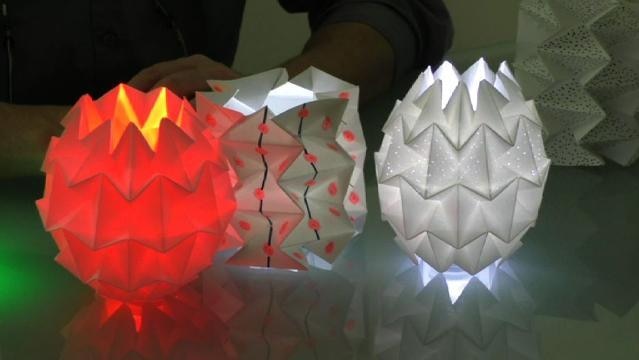Three lamps folded from paper, glowing when lit from inside