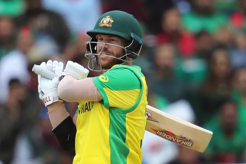 David Warner holds the bat over his shoulder and watches on after completing a shot.