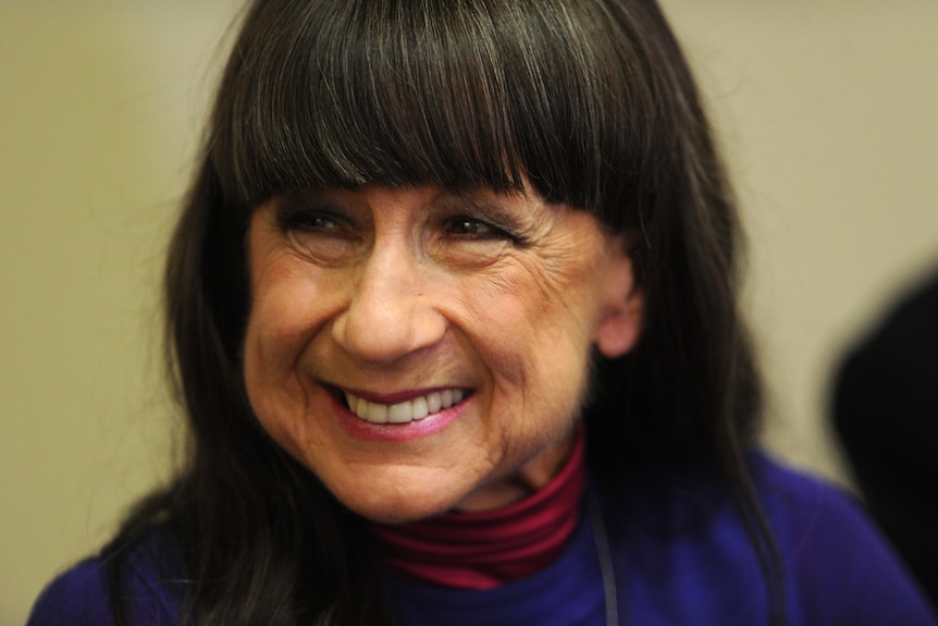 Judith Durham, who has brown hair with a fringe, smiles with softly crinkled eyes.