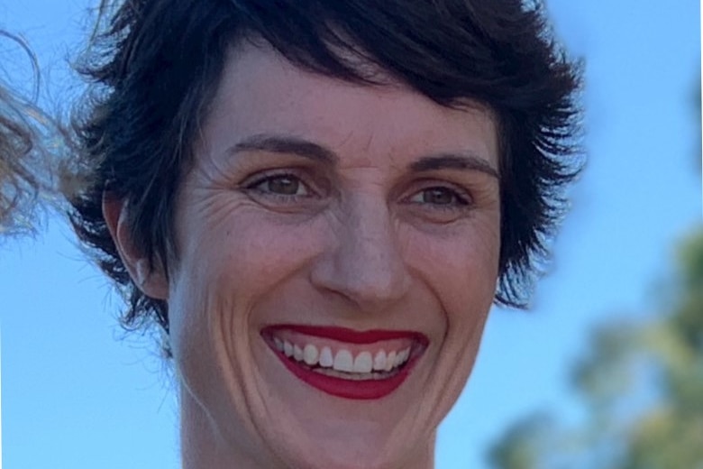A close up photo of Anna smiling against a blue sky