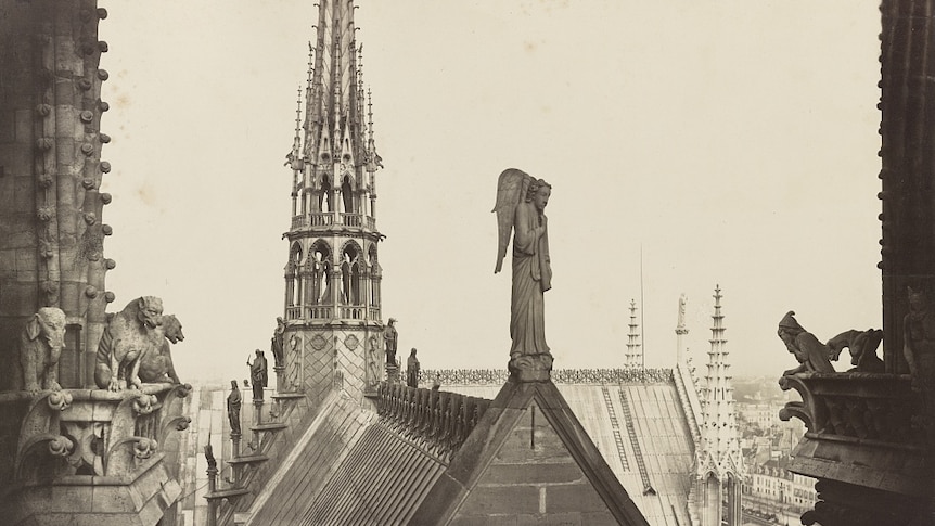 A black and white image shows the roof of the Notre Dame cathedral adorned with gargoyles and angel statues.
