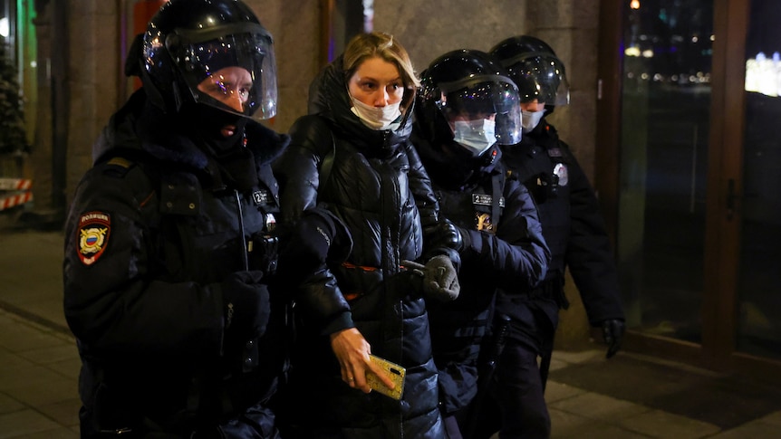 A woman is carried away by police after being detained during an anti-war protest