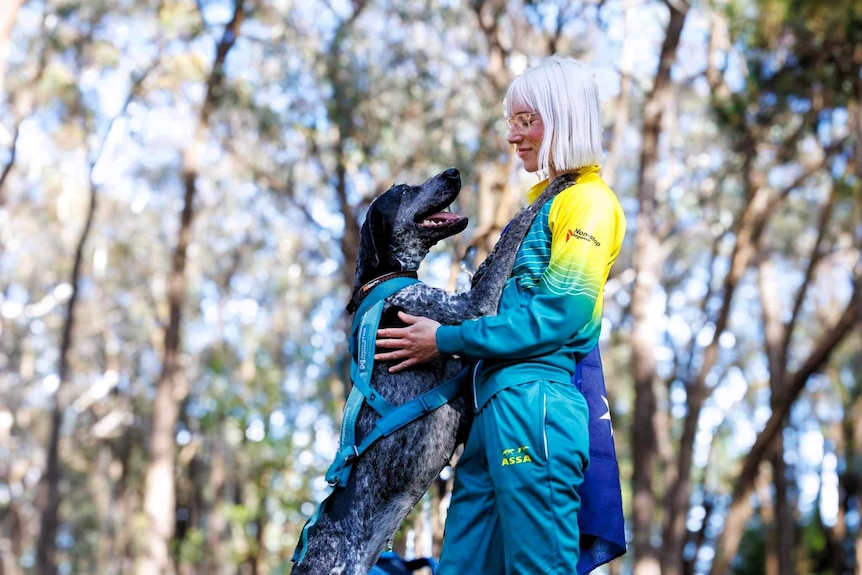 A woman stands with a dog stretched up against her with its paws on her shoulders