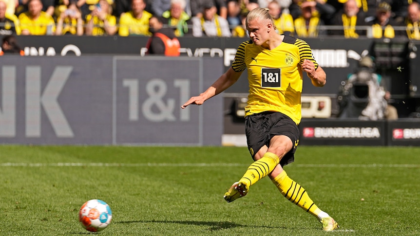 A tall striker follows through after side-footing the ball home to score a penalty in the Bundesliga.