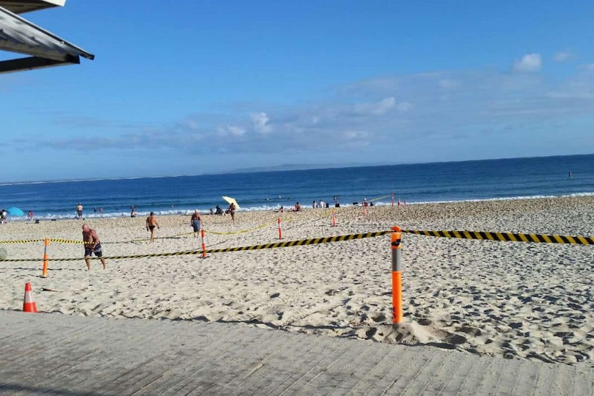 A beach cordoned off with yellow and black tape