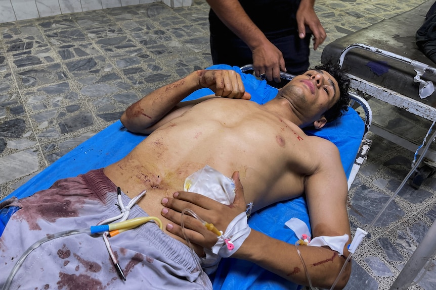 An injured man lays on a stretcher in a hospital in Iraq.
