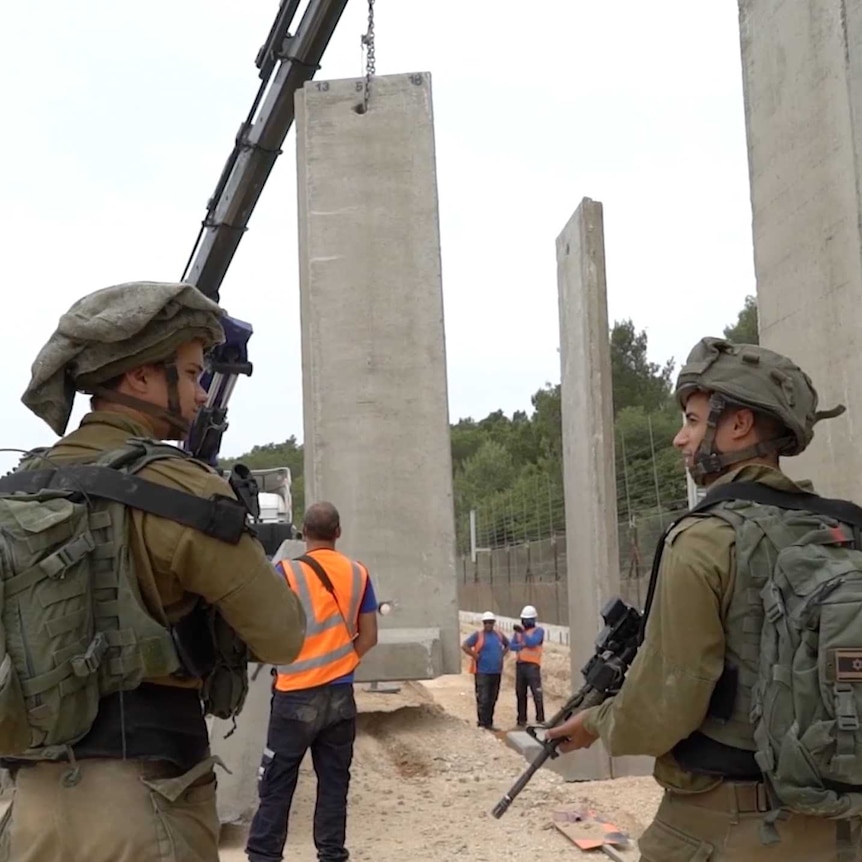 Soldiers watch the Blue Line wall being built