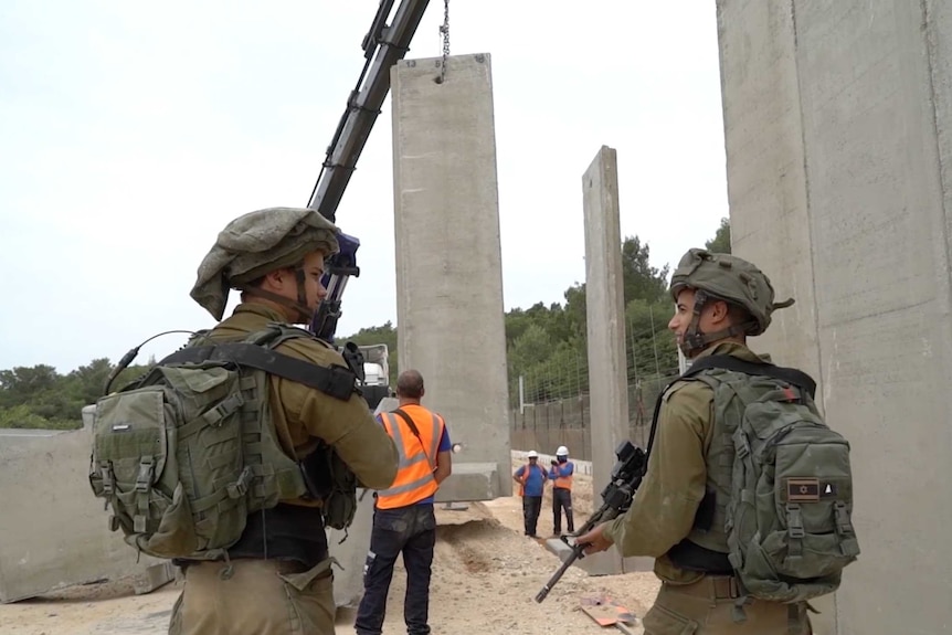 Soldiers watch the Blue Line wall being built
