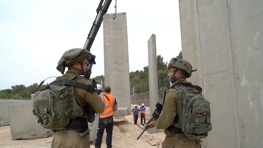 Soldiers watch the Blue Line wall being built