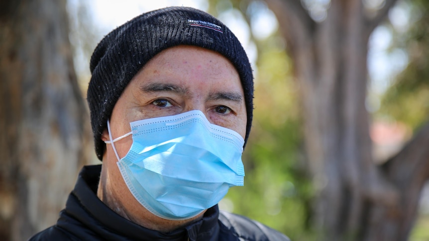 A man with a beanie wearing a mask looking ahead.