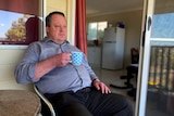 Man sits with his tea on his balcony