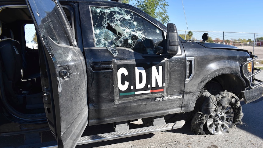 A truck with the letters CDN on the side has its windows and tyres destroyed after being shot.