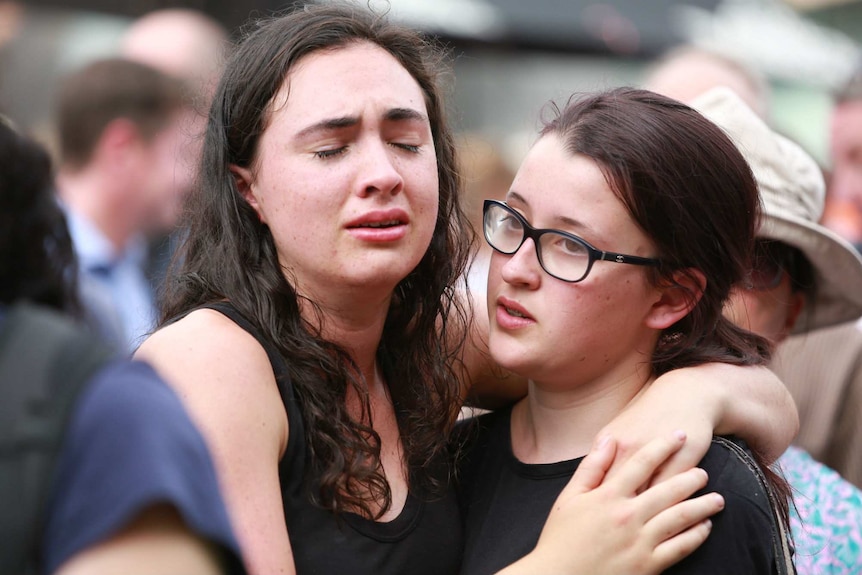 Two women cry at the vigil.