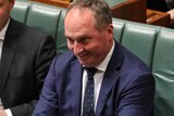 Barnaby Joyce sneers while crossing his arms in front of him. Christopher Pyne and Josh Frydenberg sit on either side.