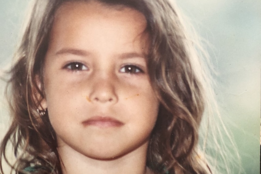 A school photo of a girl with long brown hair in a polo shirt.