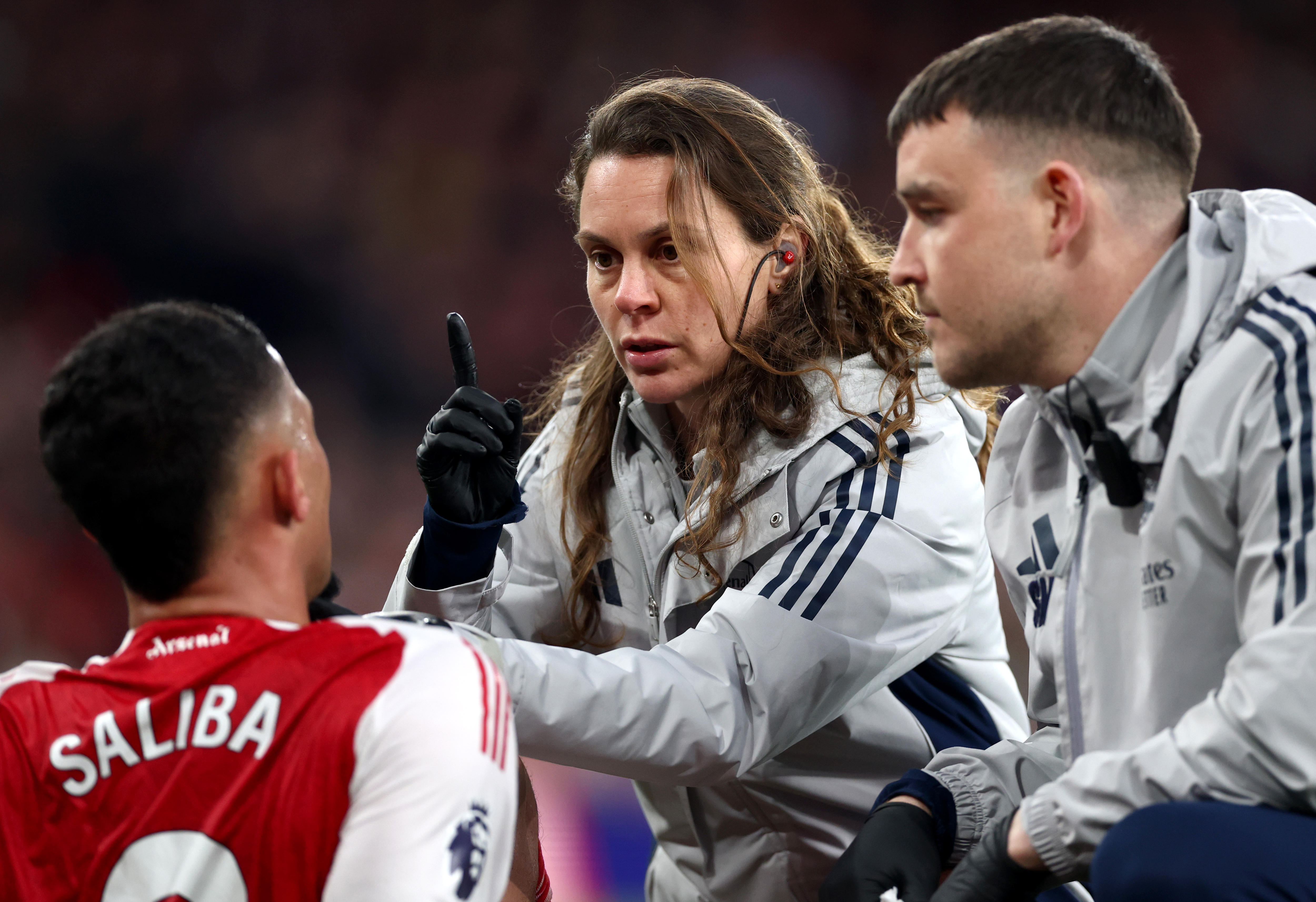 A club doctor points a finger in front of an Arsenal player to conduct a concussion test during a game.