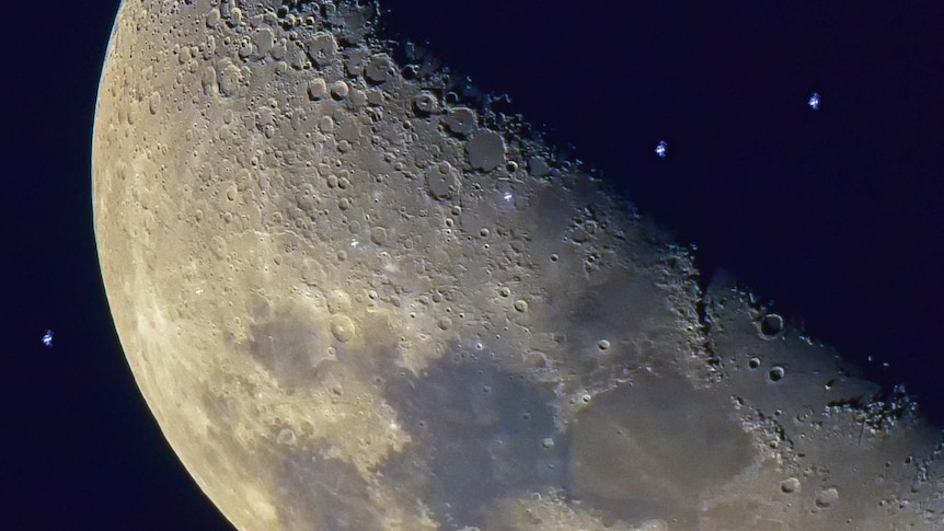 This photo shows the International Space Station as it passes the surface of the moon.