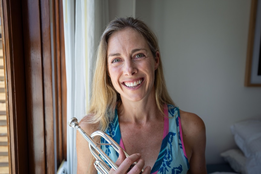 Belinda Pratten facing the camera front on, smiling and holding her trumpet.
