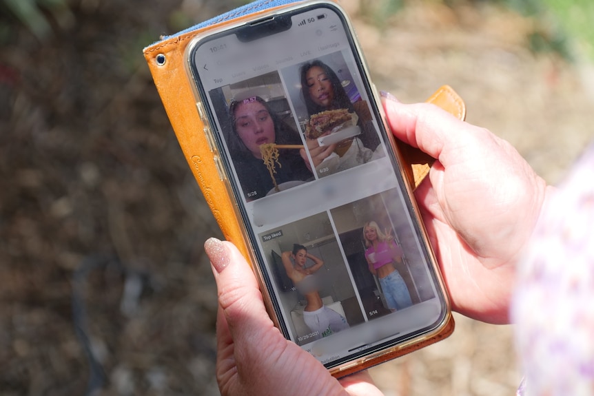 A woman holding a phone, looking at videos of people eating and posing in crop tops