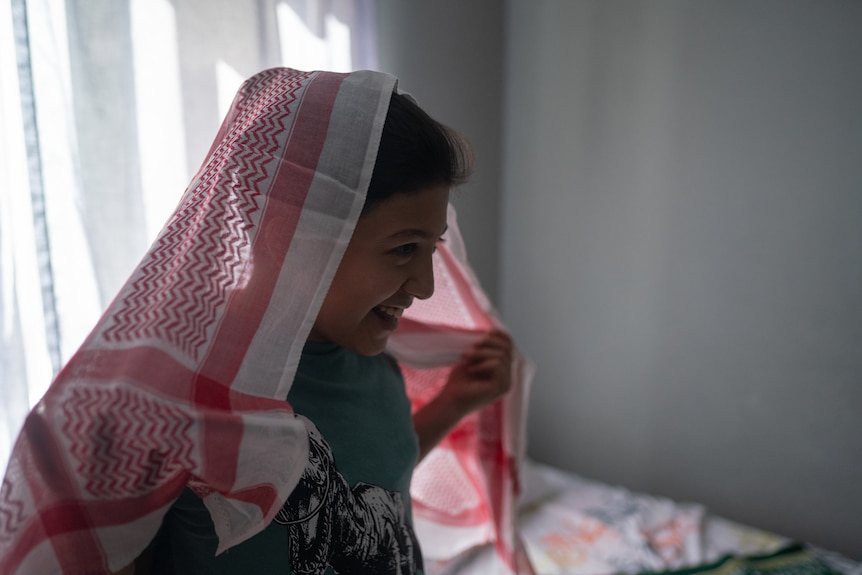 A young boy plays with a head scarf.