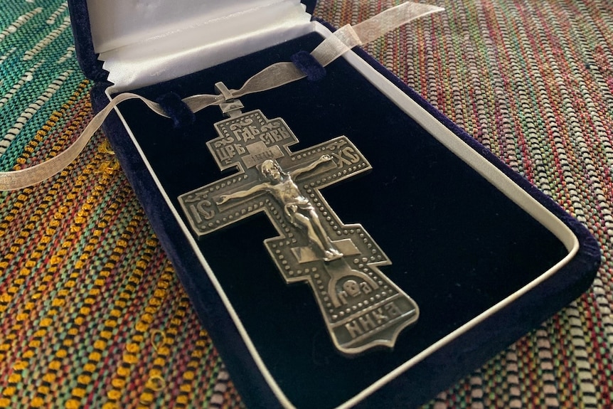 Metal military cross in a dark blue case.